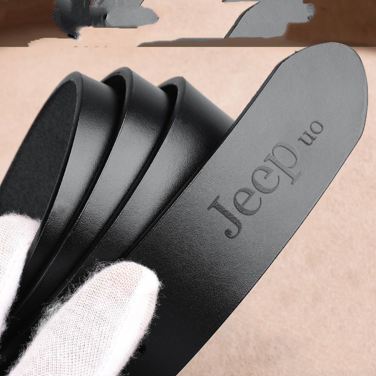 Close-up of black two-layer cowhide men's belt with embossed Jeep logo, showcasing smooth leather texture and durable craftsmanship.